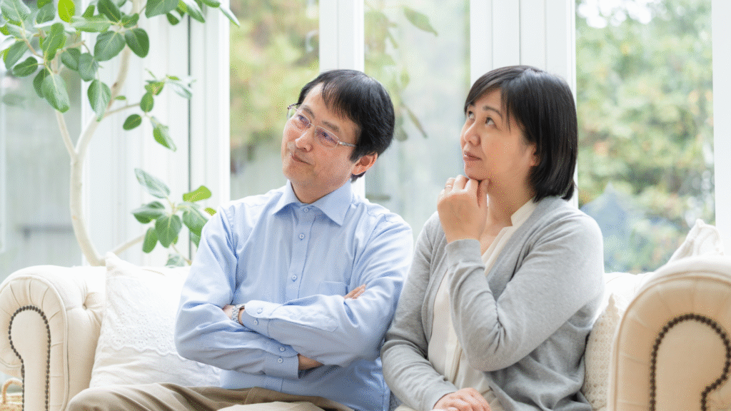 ソファーに座って悩んでいる壮年夫婦