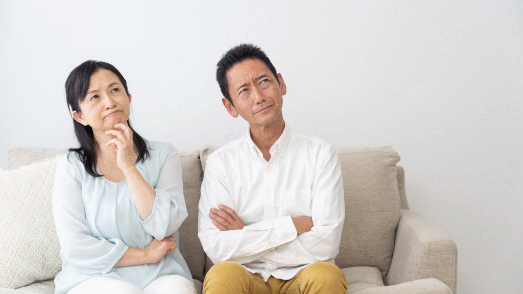 ソファーに座って悩んでいる壮年夫婦