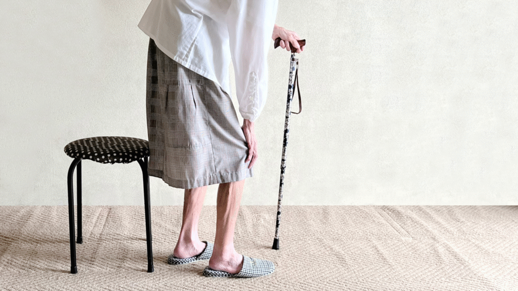 杖をついて立ち上がっている痩せた高齢女性