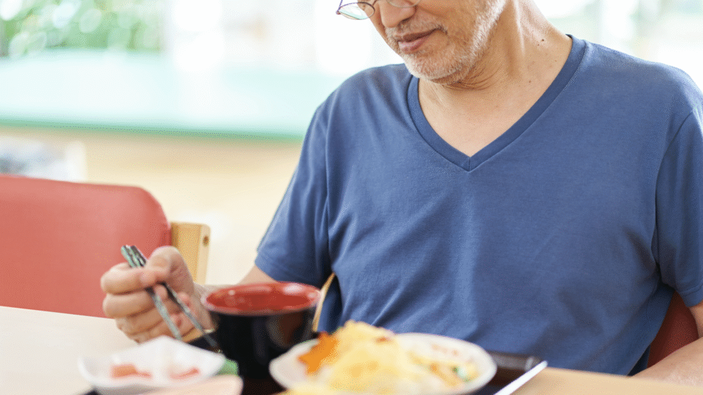 寂しそうに一人で食事を食べている高齢男性