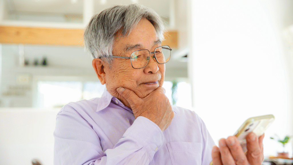 スマホを見て悩んでいる高齢男性