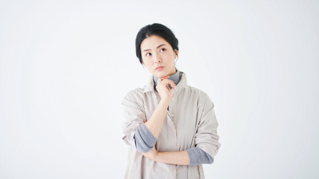 あごに手を置いて悩んでいる中年女性