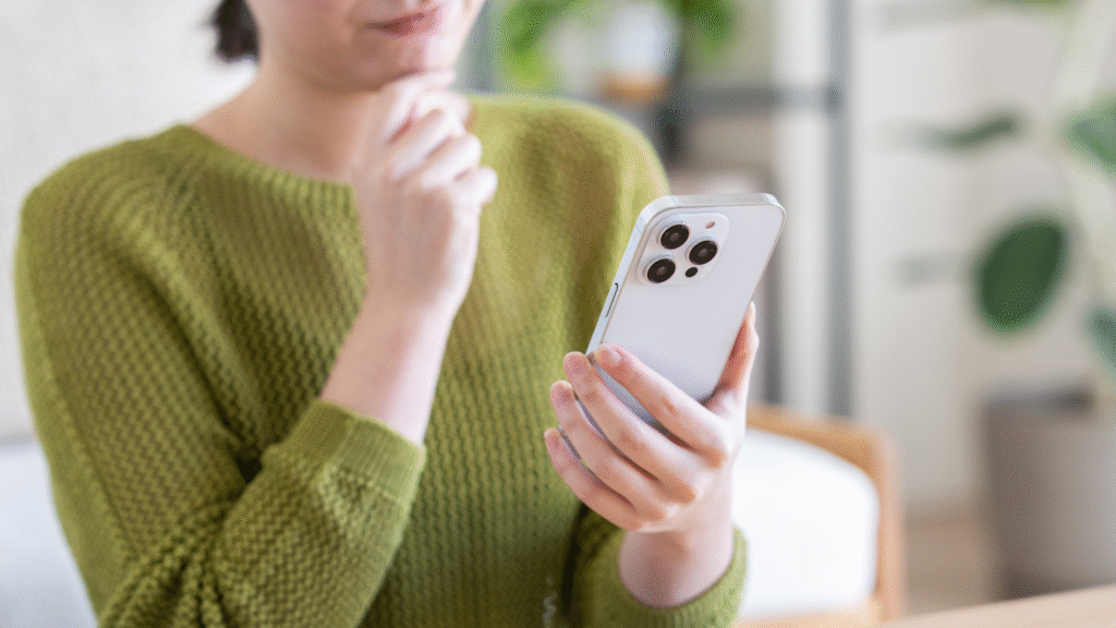 スマホ見て悩んでいる様子の中年女性の手元